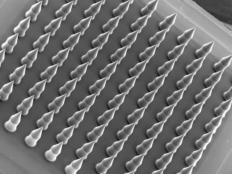 lines of microneedles in grey with a glow around the edges, arranged on a tilted plate