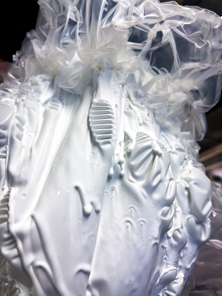 white glue drips in sheets, gauze-like at the top, pleated in the middle and sheet-like at the bottom